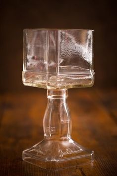 a glass candle holder sitting on top of a wooden table