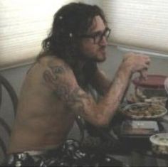 a shirtless man sitting at a table with food