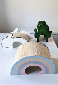 two wooden animals sitting on top of a white table next to a green cactus plant