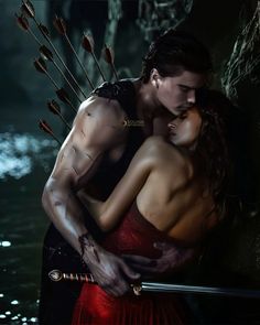 a man and woman embracing in front of water with arrows sticking out of their mouths