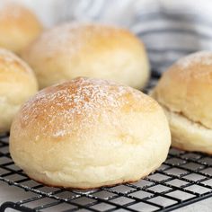 several rolls on a cooling rack with powdered sugar sprinkled on top, ready to be baked