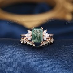 a ring with an emerald stone surrounded by small white and green stones on top of it