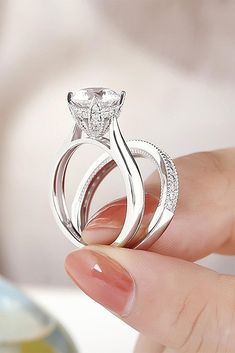 a close up of a person holding two rings in their hand with the ring setting on top