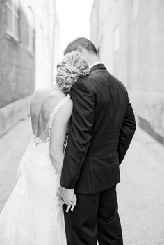 a bride and groom standing in an alleyway hugging each other for a kiss on their wedding day