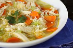 a white bowl filled with cabbage and carrots on top of a blue table cloth