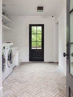 a washer and dryer in a white room with brick flooring on the walls