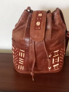 Our Afrocentric design, artisan-made Shoulder bags is a must for your holiday wish list. Made in Africa with uniquely colorful prints. Handmade Leather Bucket Bag For Travel, Unique Brown Travel Shoulder Bag, Unique Brown Shoulder Bag For Travel, Brown Pouch Shoulder Bag For Market, Unique Rectangular Leather Bag, Unique Leather Bag As A Gift, Bohemian Brown Bucket Bag As Gift, Traditional Brown Bag With Leather Lining, Unique Natural Bag For Everyday Use