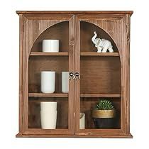 a wooden bookcase with glass doors and shelves filled with candles, vases and other items