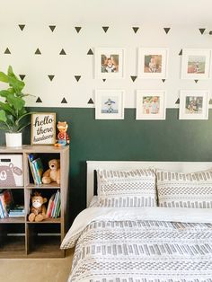 a bedroom with green walls and pictures on the wall above the bed, along with a teddy bear