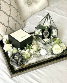 a tray that has flowers and a bottle on it with a pillow in the background