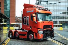 an orange semi truck driving down the street