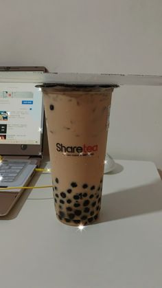 a coffee cup sitting next to a laptop computer on a white table with the lid open