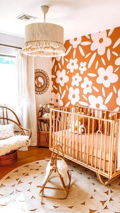 a baby's room with a crib, rocking chair and large flowered wallpaper