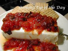 two pieces of cheese covered in sauce on a plate with crackers next to it