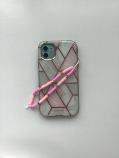 an iphone case with pink beads and a tassel on the back, sitting on a white surface