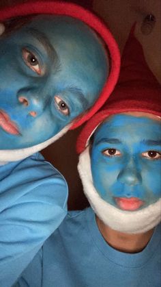 two boys with blue face paint on their faces and one boy wearing a santa hat