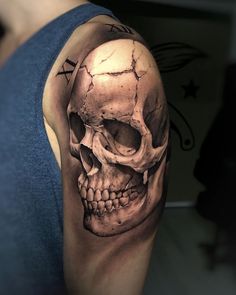 a man's arm with a skull and cross tattoo on the upper half of his arm