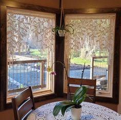 a dining room table with a vase on top of it next to two large windows