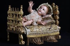 a baby doll sitting on top of a golden chair