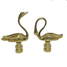 two brass swan figurines sitting side by side on top of each other in front of a white background