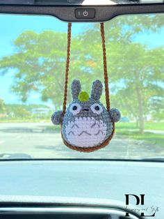 a crocheted animal hanging from the side of a car's dash mirror