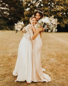 two women standing next to each other holding bouquets in their hands and smiling at the camera