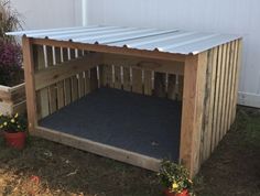 a dog house made out of pallet wood with a metal roof and blue mat