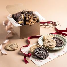 three cookies and two brownies in a box on a table with ribbon around it