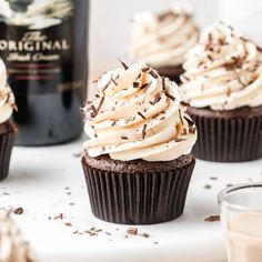 chocolate cupcakes with white frosting and sprinkles next to a bottle of wine