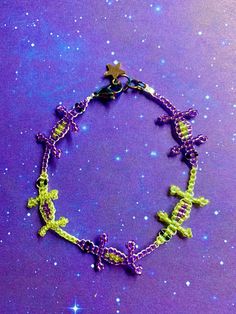 a purple and green bracelet with cross charms on it's end, against a background of stars