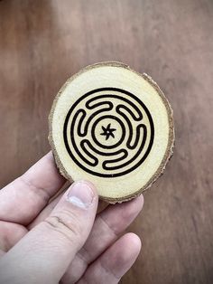 a hand holding a piece of wood with a design on it that looks like a maze