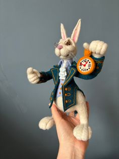 a stuffed rabbit in a suit and tie holding an orange clock on it's back