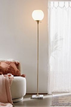 a living room with a white couch and a gold floor lamp