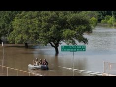 several people in a small boat traveling down a flooded street with a sign on it