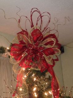 a christmas tree with red and white bows on it's top, surrounded by lights