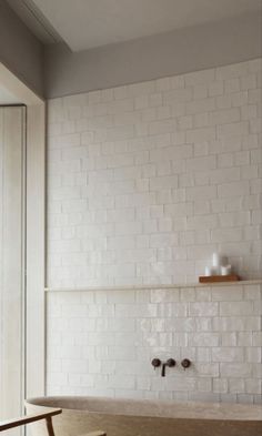 a bath tub sitting under a window next to a wooden shelf filled with cups and vases