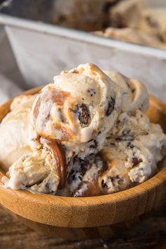 two scoops of ice cream in a wooden bowl on a table with other dessert items