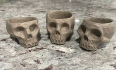 three clay skulls sitting on top of a counter