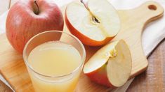 an apple and some juice on a cutting board