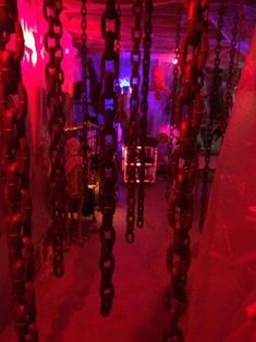 chains hanging from the ceiling in a room with red lights and other items on display