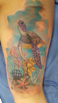 a woman's leg with a turtle and corals tattoo on the side of her thigh