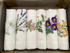 a box filled with white napkins covered in different types of floral embroidered on them