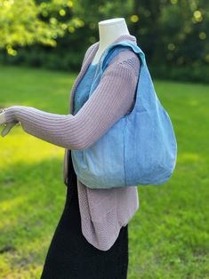 a mannequin wearing a blue bag in front of a grassy area with trees