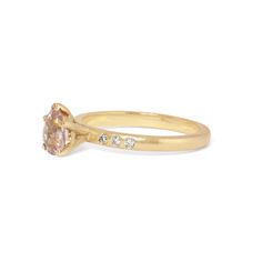 a yellow gold ring with an oval shaped morganite and three diamonds on the band