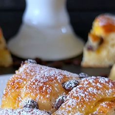 powdered sugar covered pastry sitting on top of a white plate next to other pastries