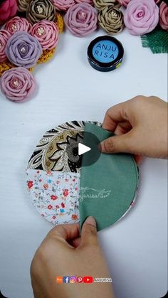 someone is making a flower arrangement out of fabric and paper with flowers in the background