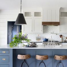 two stools are in front of the kitchen island with blue cabinets and white countertops