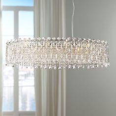 a crystal chandelier hanging from the ceiling in a room with white walls and windows