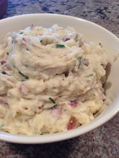 a white bowl filled with mashed potatoes sitting on top of a counter next to a purple container