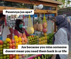 two people wearing masks standing in front of a fruit stand